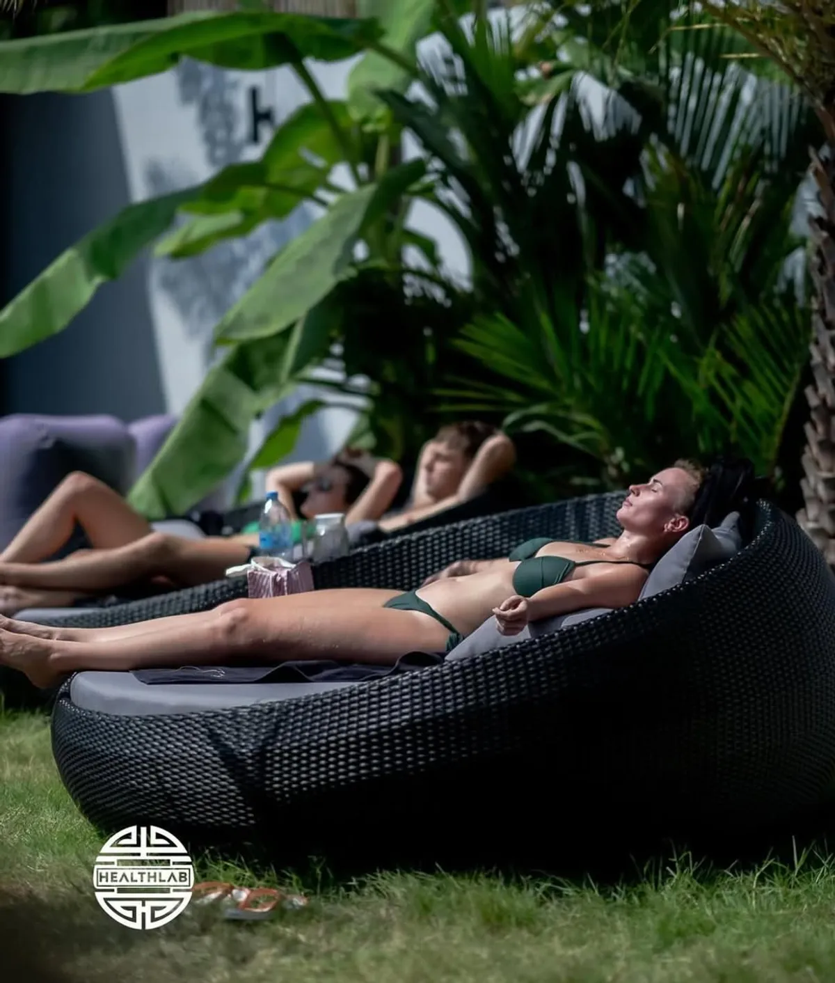 Guests relaxing on daybeds in the Healthlab tropical garden